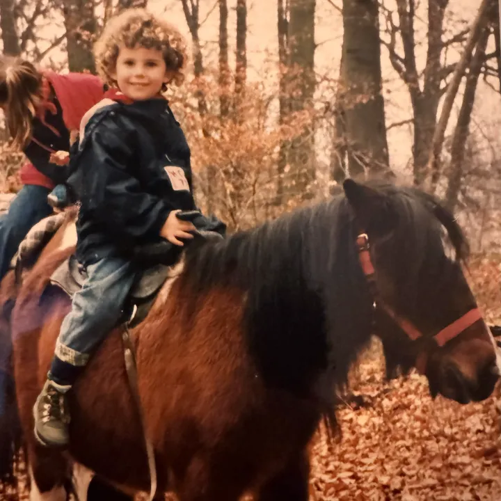 Kind auf einem Shetlandpony bei einem Spaziergang im herbstlichen Wald